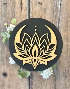 a black and gold lotus flower on a wooden background with white flowers around the edges