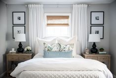 a bed with white sheets, pillows and pictures on the wall