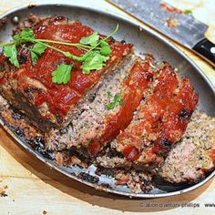 meatloaf with marinara sauce and parsley in a pan next to a knife