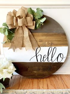 a wooden sign with the word hello on it next to flowers and a potted plant