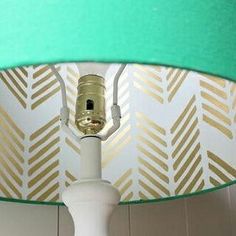 a white table lamp with a green shade on the bottom and gold trim around it