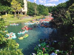 a river filled with lots of people floating down it's sides next to a tall building