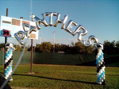 an outdoor basketball court with balloons that spell out the word happy on it and two hoopers in the shape of letters