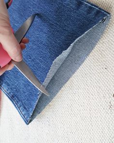 someone is cutting through the side of a pair of jeans with a scissor