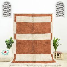 a brown and white rug sitting on top of a wooden floor next to a potted plant