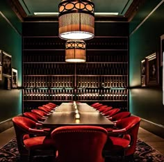 a long table with red chairs and a chandelier hanging from it's ceiling