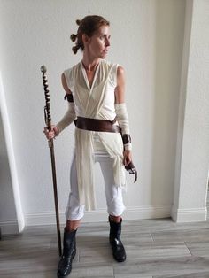 a woman is dressed up as star wars character luke sky walker and holding a staff