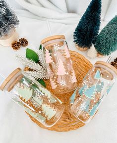 four glass tumblers sitting on top of a wicker basket next to christmas trees