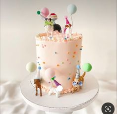 a birthday cake decorated with balloons and dogs on the top is pink frosting, topped with confetti