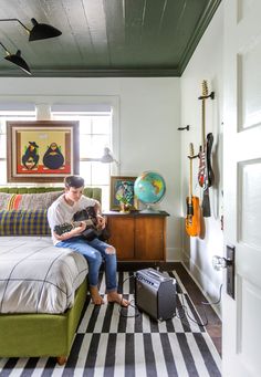 a woman sitting on top of a bed next to a green couch in a bedroom