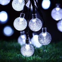 some lights that are hanging from a tree in the grass with snow flakes on them