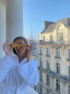 a woman in a bathrobe looking at the camera with her hands up to her face