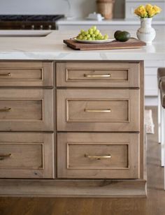 a kitchen island with drawers and fruit on it in front of a stove top oven