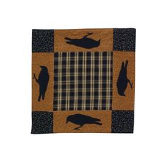 a black and brown quilt with silhouettes of birds on the front, sitting on a checkered table cloth