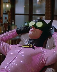 a man in a pink costume with cucumbers on his head and glasses laying down