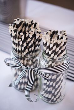 black and white striped paper straws in a mason jar with ribbon on the side