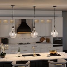 a large kitchen with white cabinets and marble counter tops is lit by pendant lights that hang from the ceiling