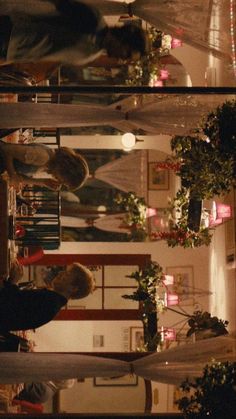 two people sitting at a table in a room with plants and candles on the walls