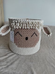 a knitted sheep basket sitting on top of a bed