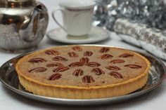 a pecan pie sitting on top of a metal pan next to a cup and saucer