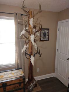 an antler tree with deer heads on it in the corner of a living room