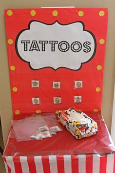 a red and white striped table topped with a cake covered in frosting next to a sign that says tattoos