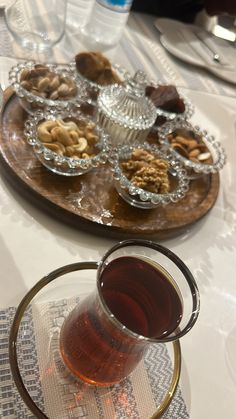 a table topped with plates and cups filled with desserts next to glasses of wine