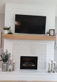 a fireplace with a flat screen tv mounted above it and other decorations on the mantle