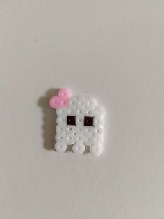 a white sheep with a pink bow on it's head is made out of beads