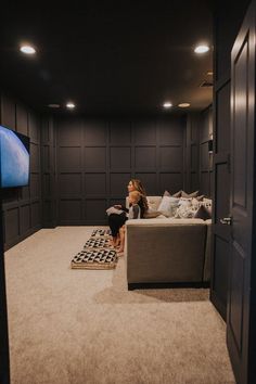 a woman sitting on top of a couch in a living room next to a tv