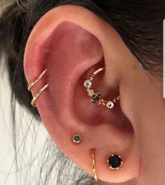 an ear with three different types of piercings on it's sides and one is in the middle