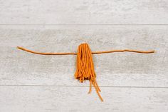 an orange piece of yarn is laying on the floor with it's end twisted up