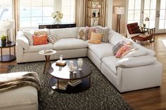 a living room with white couches and blue pillows on the sofa, along with other furniture