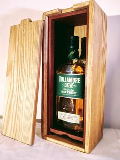 a bottle of tullamore dew sitting in a wooden box on a white surface