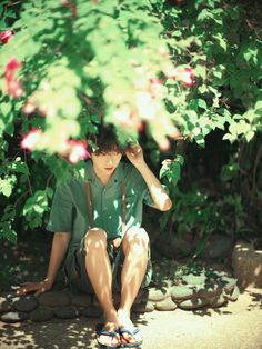 a boy sitting on the ground under a tree