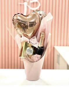 a pink vase filled with champagne and heart shaped balloons