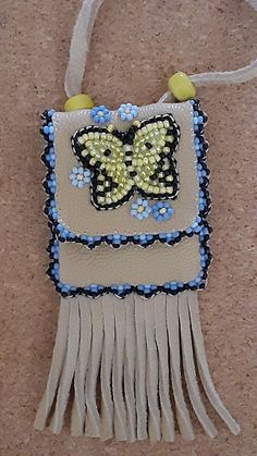 a white purse with blue beads and a yellow butterfly on it's back hanging from a string