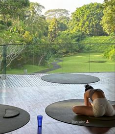 a woman laying on the ground in front of a glass wall and looking out at trees