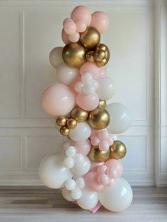 a bunch of balloons that are in the shape of a tower with gold, pink and white balloons