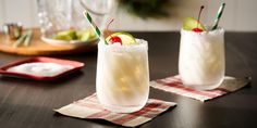 two glasses filled with drinks sitting on top of a table