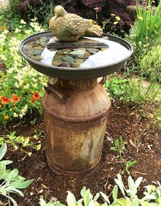 a bird bath sitting on top of a water fountain in the middle of a garden