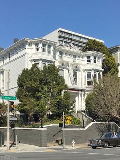 an old car is parked on the street in front of a large white building with many windows and balconies