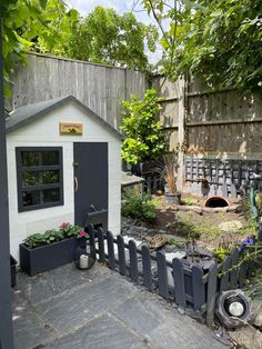 a small white shed sitting in the middle of a yard next to a wooden fence