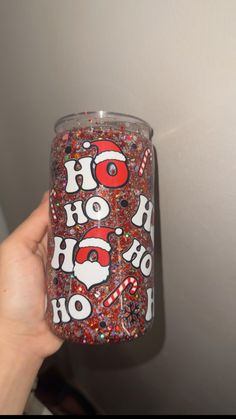 someone is holding up a glass with the words ho ho ho and candy canes on it