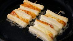 four pieces of food cooking in a frying pan