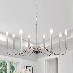 a chandelier hanging from the ceiling in a room with white walls and windows