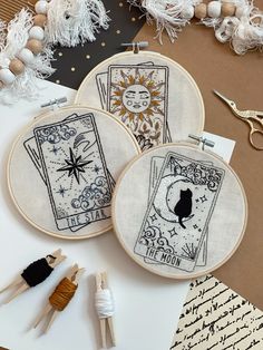 two embroidery hoops with pictures on them next to scissors and other crafting supplies