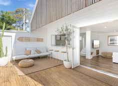 an outdoor living room with wood floors and white furniture on the outside wall, along with a wooden deck