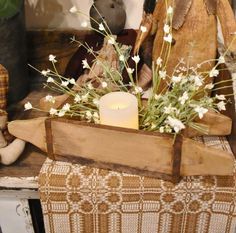 a teddy bear sitting next to a candle in a wooden crate with flowers and candlesticks