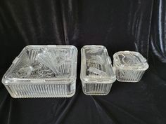 three clear glass dishes with lids on a black background